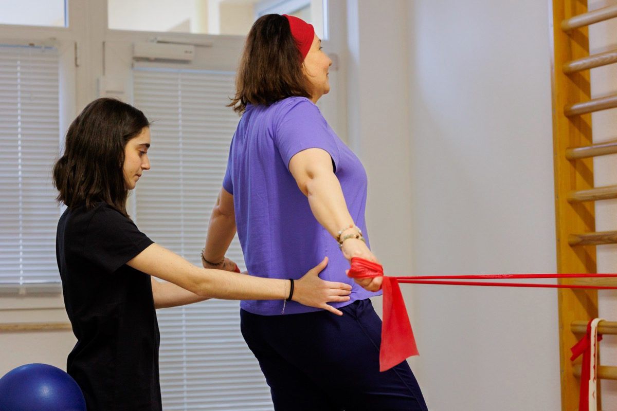 Therapist guiding a movement exercise with an elastic band